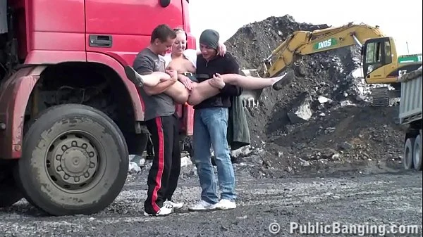 A very cute blonde young lady is fucked in public threesome at a construction site