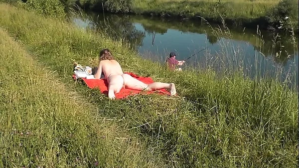 MILF sexy Frina on river bank undressed and sunbathes naked. Random man fisherman watching for her, and in the end decided to join naked woman. Wild beach. Nudist beach. Public nudity. Public exposure. Naked in public